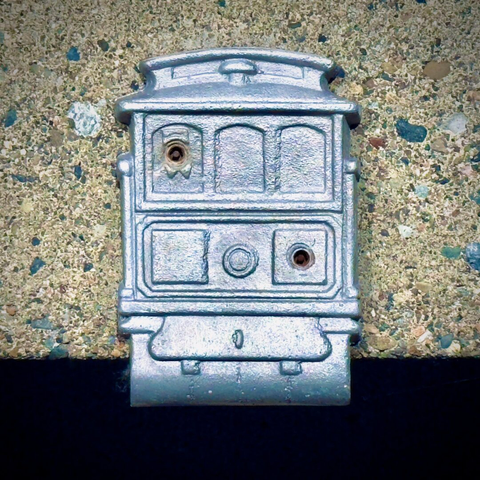 A close-up view shows a metallic streetcar design screwed down to the concrete ledge beneath it.
