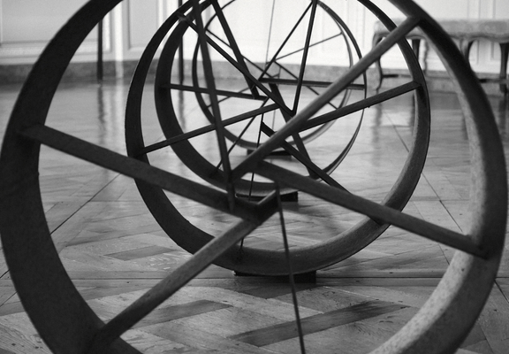 Photo en noir et blanc d’un alignement de cylindres métalliques avec des branche en leur intérieur qui forment une espèce de spirale
