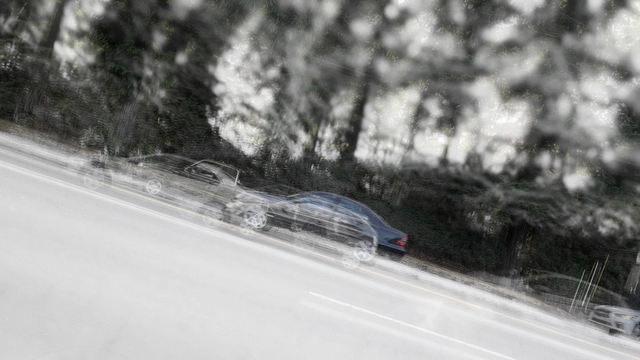 A photograph of a street with trees and landscape in the immediate background, inclined by ~30 degrees to the left, with the bottom right corner of the frame as the starting point of the road. Layers of cars passing by, with one color photo slightly colored, giving the impression of ghosts of cars over time. With post-process tilt-shift blur, the focus is on the cars but also implies a view from memory.