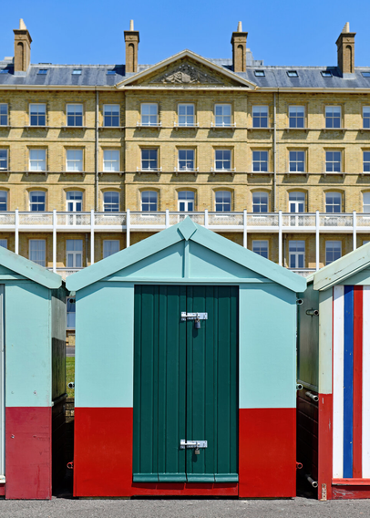 Photo of a Hove Lawns beach hut with Kings House in background. The gable of the beach hut has similarity with the pediment on the building behind. City of Brighton & Hove, Sussex, UK.