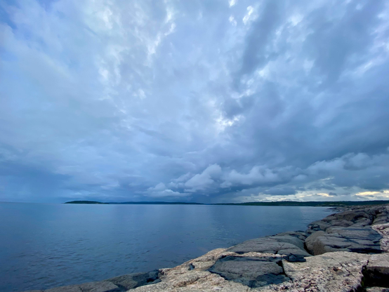 The sky with clouds, water reflects the sky, the rock