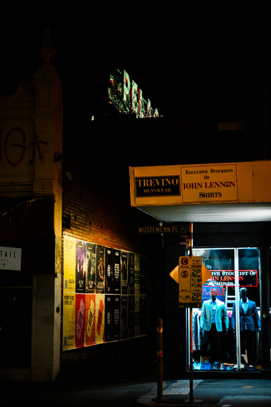 A dark alley is lit by a shopfront with mannequins in suits