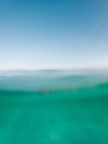 Photo of the ocean surface with a person standing on a stand up paddle in the distance