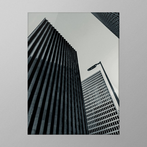 A black and white photo showing a low angle view of tall office buildings. Everything is straight lines.