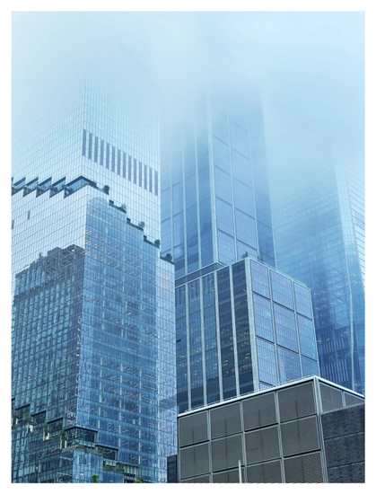 Blue-toned photo of closely-grouped skyscrapers with their upper floors disappearing into fog. Their facades are mostly grids of glass windows displaying the reflections of other high-rise buildings. The tower on the left features a row of larger windows in a descending-step pattern echoed by a rooftop terrace several floors above. In the foreground is a low, gray building with a grid of square windows covered with horizontal slats.