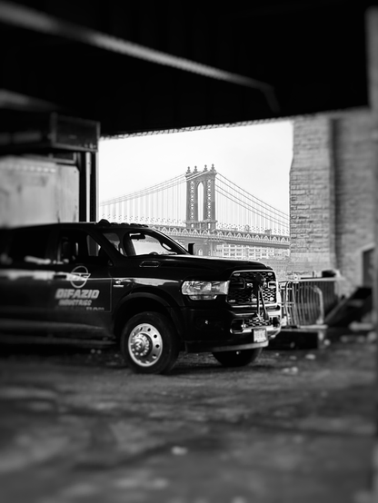 A truck parked in a construction area by the East River. In the distance is the Manhattan Bridge 