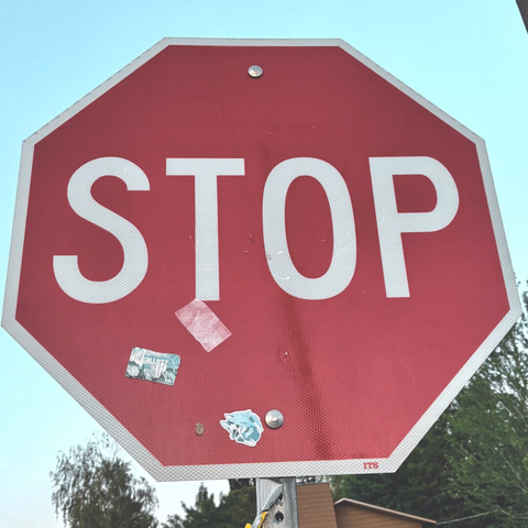 A stop sign with a few stickers stuck to it.