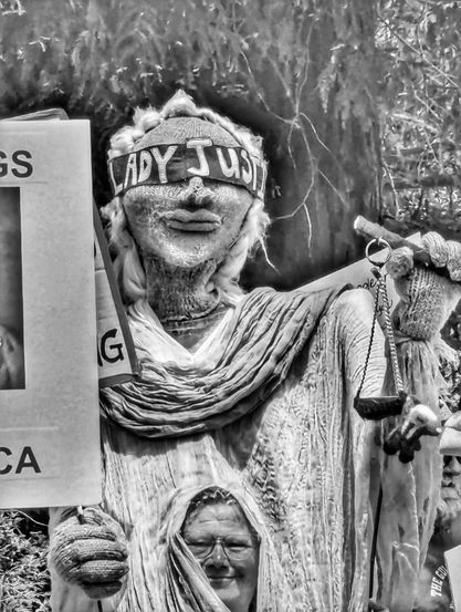 A person with a large "Lady Justice"  pantomime puppet.