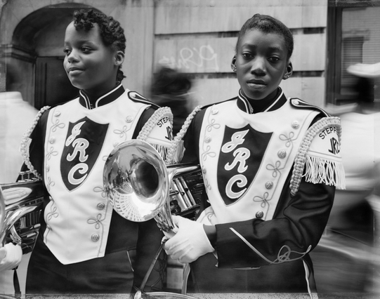 deux jeunes musiciennes noires d’une fanfare à Harlem, en tenue de défilé, leur instrument à vent sous le bras