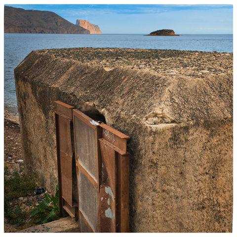 Im Vordergrund ein Bunker von 1937 aus dem spanischen Bürgerkrieg, korrodierter Beton und rostige Einstiegsluke, im Hintergrund das Meer und die Felsnadel des Penyal d'Ifac 