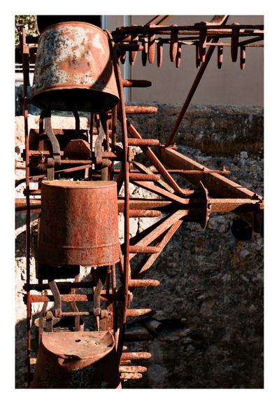 Picture of an old scoop wheel, used to lift water out of a well, nowadays no longer in use and covered in Rust.