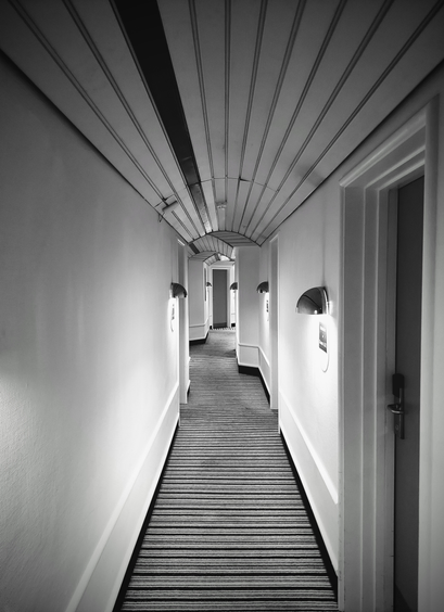 hotel corridor, vaulted but low wood-panelled ceiling, bend in corridor giving an oddly cramped feeling