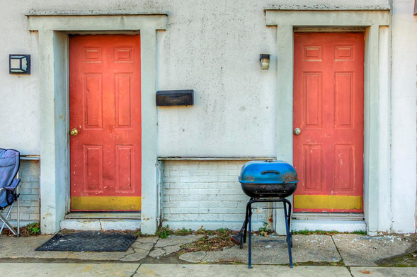 Grill Between 2 Doors

Two red doors stand side by side on a stucco wall, each with a small light fixture above them.