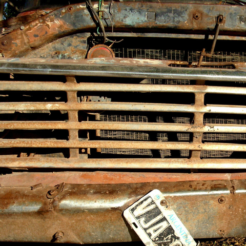 The image shows a close-up view of the front of an old, rusted vehicle, likely a truck, with a focus on the grille and radiator. The grille is made of horizontal metal bars, some of which are rusted and discolored, indicating significant age and exposure to the elements. The radiator behind the grille is also visible, with a similar rusted appearance. The vehicle's paint is peeling and faded, with patches of rust and discoloration, suggesting it has been exposed to the elements for a long time. A license plate is attached to the front bumper. The license plate is slightly tilted and appears to be in good condition compared to the rest of the vehicle. The background is not clearly visible, but it seems to be an outdoor setting with some vegetation.

Provided by @altbot, generated privately and locally using Ovis2-8B

🌱 Energy used: 0.387 Wh