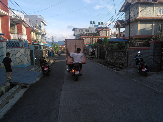 Image of a motorcycle from the back, where the person sitting in the back seat carries a wardrobe