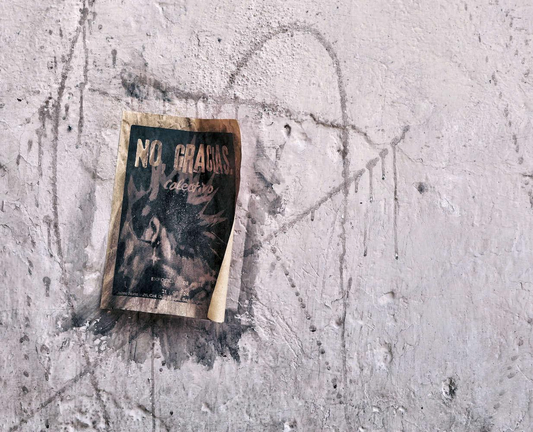 Photo of a wall with graffiti shaped like a star and a flier inscribed with the text "No, Gracias."