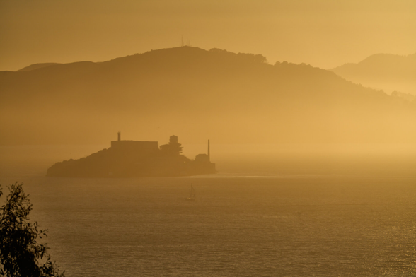 Long distance shot of Marin County with Alcatraz in the foreground. There is a haze at seal level. The light is golden.