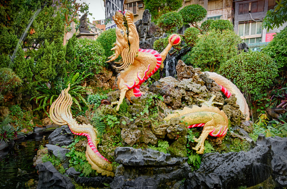 Pond on the temple premises with fountain and dragon sculpture.