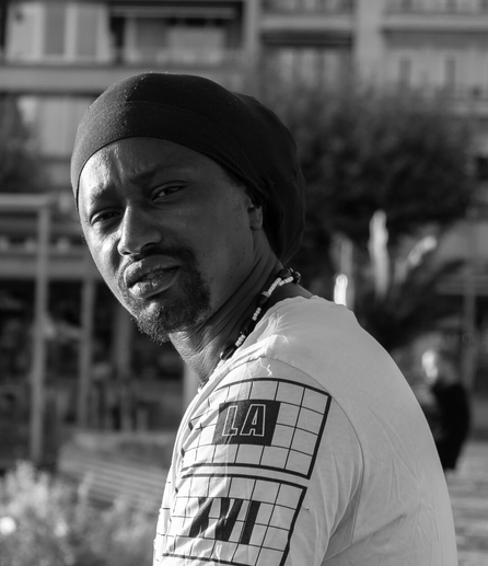 Portrait of a black man in early morning sunlight. He is wearing some kind of durag.