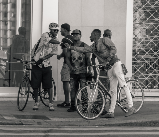 Early morning picture of a group of people finishing their night. They are fist bumping and have bikes with them.