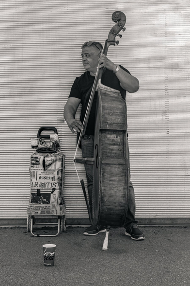 Black and white picture of a street musician playing the cello.