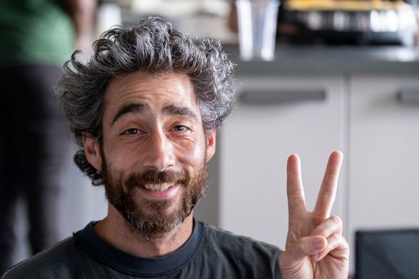 Portrait of a man smiling and making the peace sign.