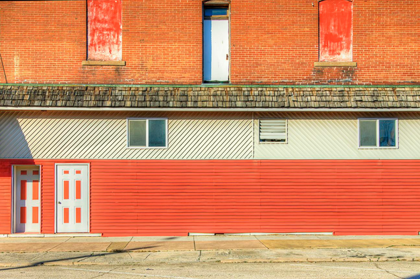 Two Doors Down

A building facade features a bold combination of red and white, with two doors and small windows. 
