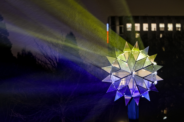 "Aurora" flower-like mirror installation outside of CCH in front of a dark rainy night.