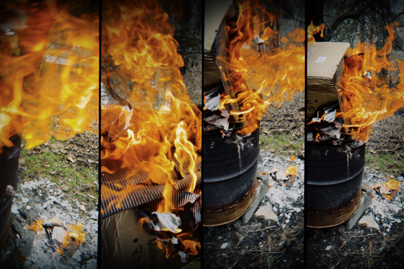 This photograph is a four-panel sequence showing a cardboard box engulfed in flames inside a metal burn barrel. Each panel captures a different moment in the burn, with swirling orange fire consuming the ridged cardboard and sending ash to the ground. The vivid motion of the flames contrasts with the still, scorched earth and scattered debris around the barrel.
