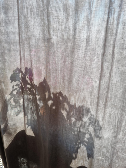 Pot de Surfinia en fleurs en transparence derrière un voile de tissu gris
