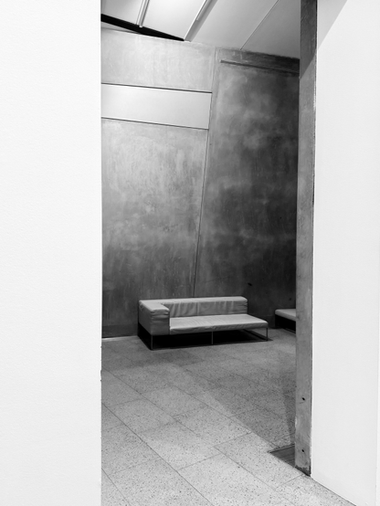 Black and white photo of a sofa chair seen through a white doorframe