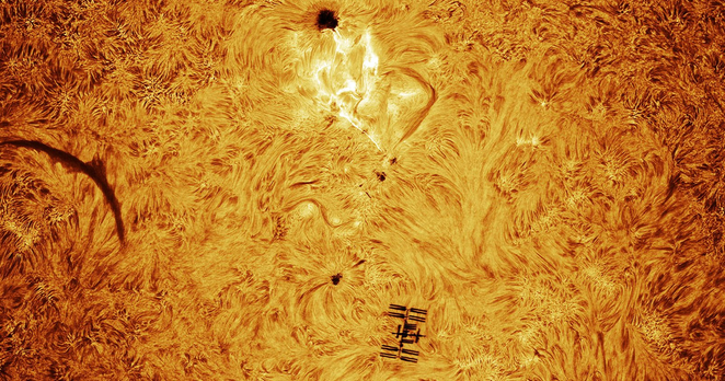 The Sun's photosphere with the silhouette of the ISS below center and a solar flare above center.