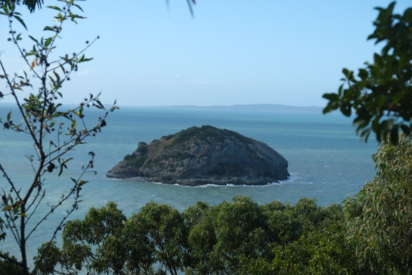 Bluff rock. A small island viewed through foliage.