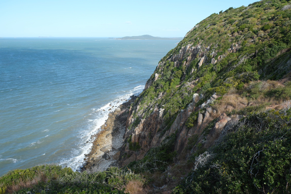 A chunk of bluff point. A large bulbous rocky cliff on the right covered in shubs leading to the sea. 