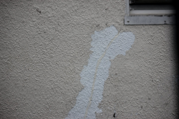 Patched crack on a beige outdoor wall. Corner of a window