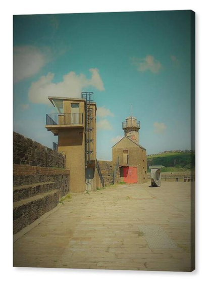 Colour portrait photograph showing three older buildings at the end of a pier beneath a blue sky.