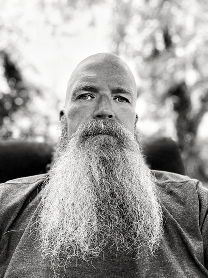 Portrait of a man with a long graying beard and a shaved head.