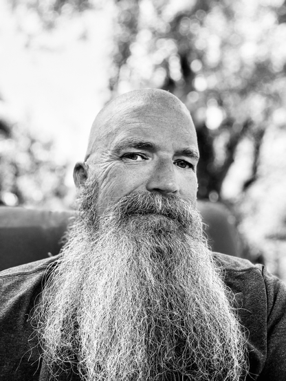 Portrait of a man with a long graying beard and a shaved head.