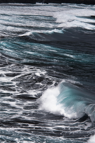 Fotografía en la q se ven olas en el oceano, en la distancia la costa rocosa