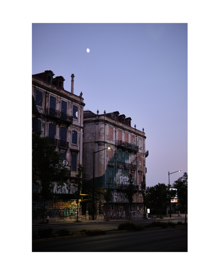 two residential buildings in lisbon in the evening with graffiti and a big mural of a crocodile, moon shining from above in misty violet sky