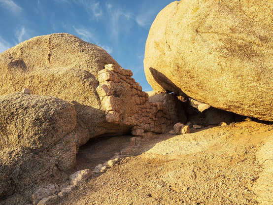Three boulders lit by sunrise light with cirrus clouds in background.