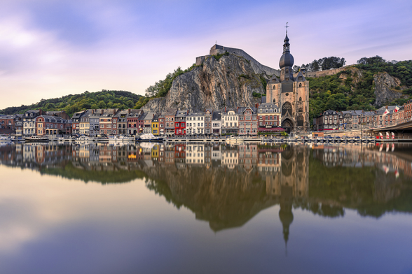 Long exposure reflection shot of Belgium's Dinant small small colourful houses and boats on the Meuse river, on a summer evening.