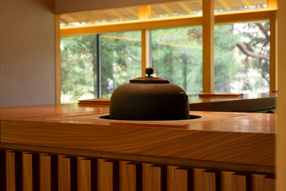 休憩所の入口すぐのところで佇む茶釜。ガラス張りの休憩所奥から外の様子が伺える。/ 2025.07.06 京都御苑・SASAYAIORI+ 京都御苑 (近衞邸跡休憩所) から