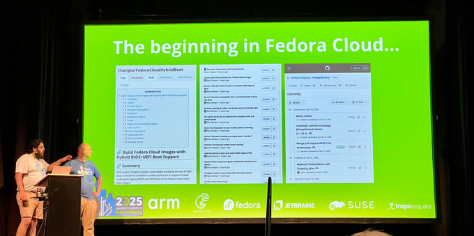 Two persons standing on a stage while presenting - the slides show some early screenshots of wiki and GitHub content