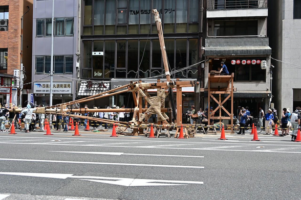 車道を挟んだ向かい側の歩道から、芯棒を建てる直前の函谷鉾の様子。/ 2025.07.11 四条烏丸・函谷鉾町から