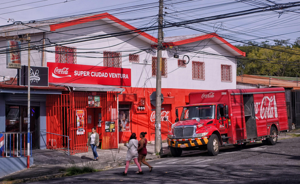 Photo of a Coca-Cola delivery truck in front of a convenience store painted with red and white Coca-Cola logos