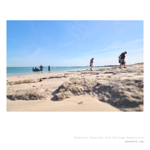 Wide shot of the beach, as passenger alight the zodiac and make their way up the sand dunes.