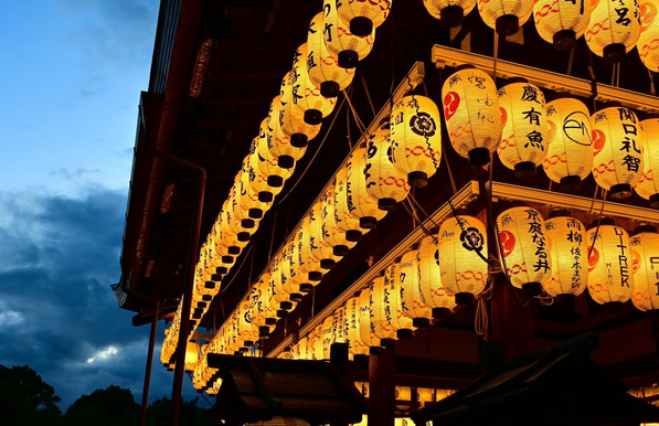 舞殿上に飾られている提灯に明かりが灯されている。/ 2025.07.19 八坂神社から