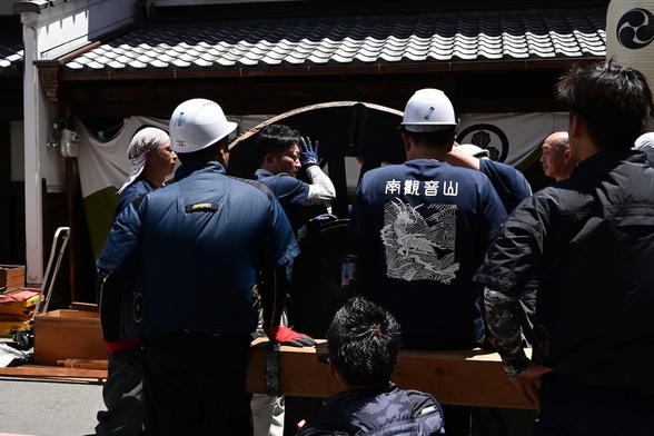 右前の車輪を所定場所まで転がして運んでいるところ。山鉾に付いた状態だと漠然と「大きいなぁ」と感じるけど、こうして人とほぼ同じ大きさの車輪を見ると改めて大きさを実感する。/ 2025.07.20 百足屋町・南観音山から