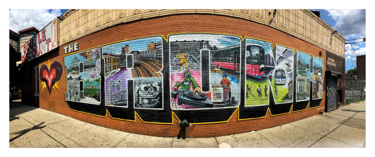 2019 photo of the iconic I LOVE THE BRONX mural on Westchester Avenue and Simpson Street in the Bronx, NY, created by the graffiti artist collective Tats Cru. From an interview with UP Magazine: “Tats Cru’s community murals preserve the culture and history of the Bronx. For I Love the Bronx, each of the letters depicts a characteristic of the Bronx with the heart painted in Bio’s trademark style. Pastimes such as children playing stickball and jump rope, dominoes, drumming, hip-hop, an ICEE seller, and the elevated trains turning the corner in a display of skill are shown alongside well-known locations such as the Bronx Botanical Garden, Bronx Zoo, and Yankee Stadium. … ‘We were brainstorming large letters with famous places in the Bronx. Things that would be cool for people on Simpson,’ BG said.”

Image description: Panorama shot of a mural on a building wall, slightly distorted so that the center bulges toward the viewer as the sides recede. The mural reads “I (heart) the Bronx” in giant letters, with the heart done in a jagged comic-book style. The tall, wide letters of “Bronx” contain community scenes as described above. A faded “Double Discount” sign hangs at the wall’s upper left, while to the right of the mural is another Double Discount logo painted over a shuttered storefront gate.

Interview source: upmag.com/up6-tats-cru/

Artist website: tatscru.biz